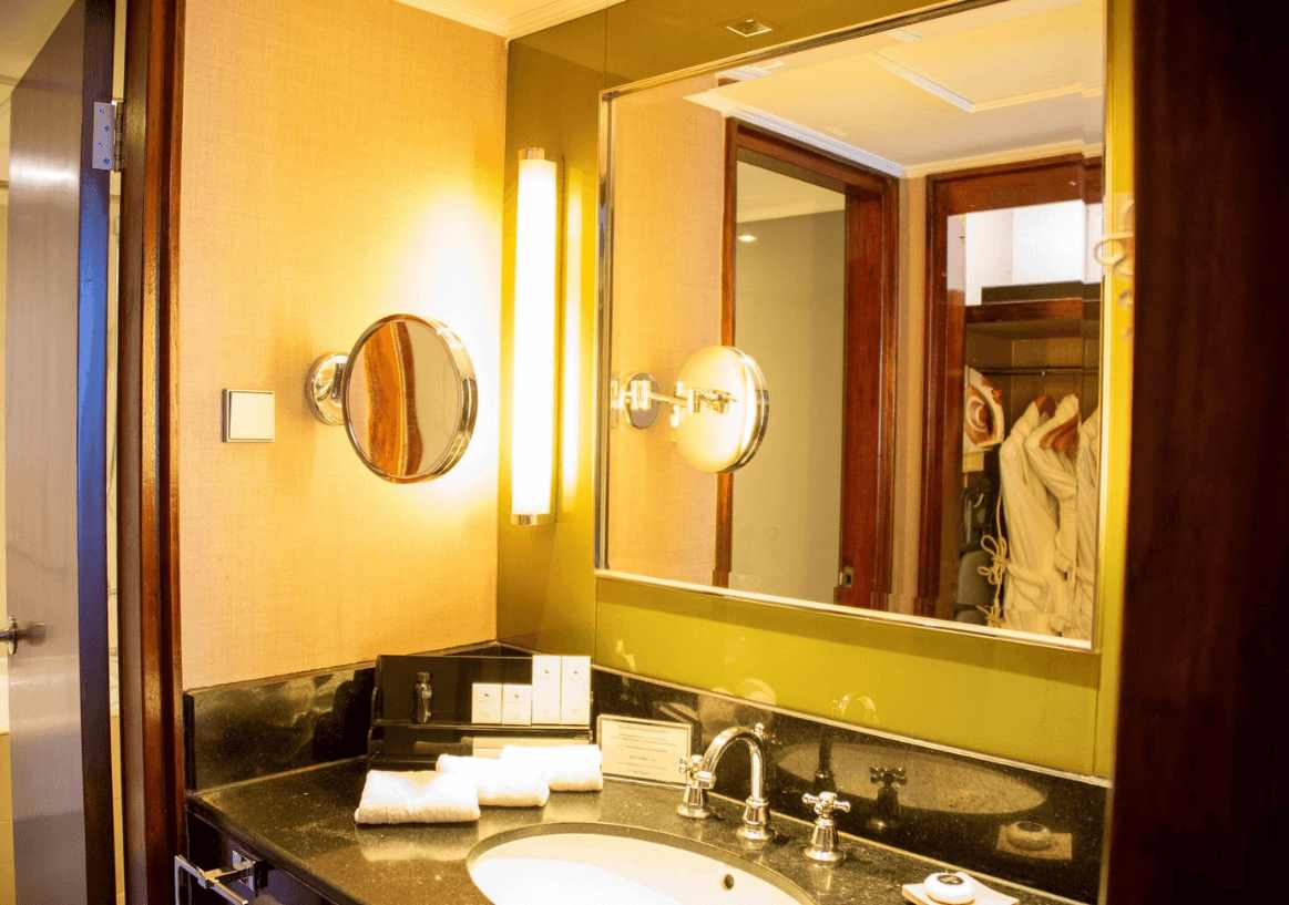 An LED mirror was displayed with a makeup mirror in a hotel bathroom illuminated with warm lighting
